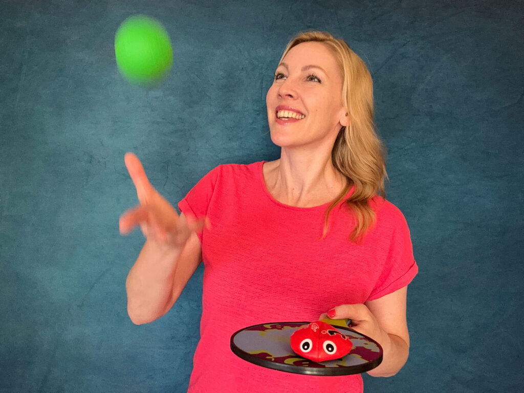 Anja Mentzendorff wirft lachend einen grünen Ball hoch und hält ein Fangbrett in der Hand