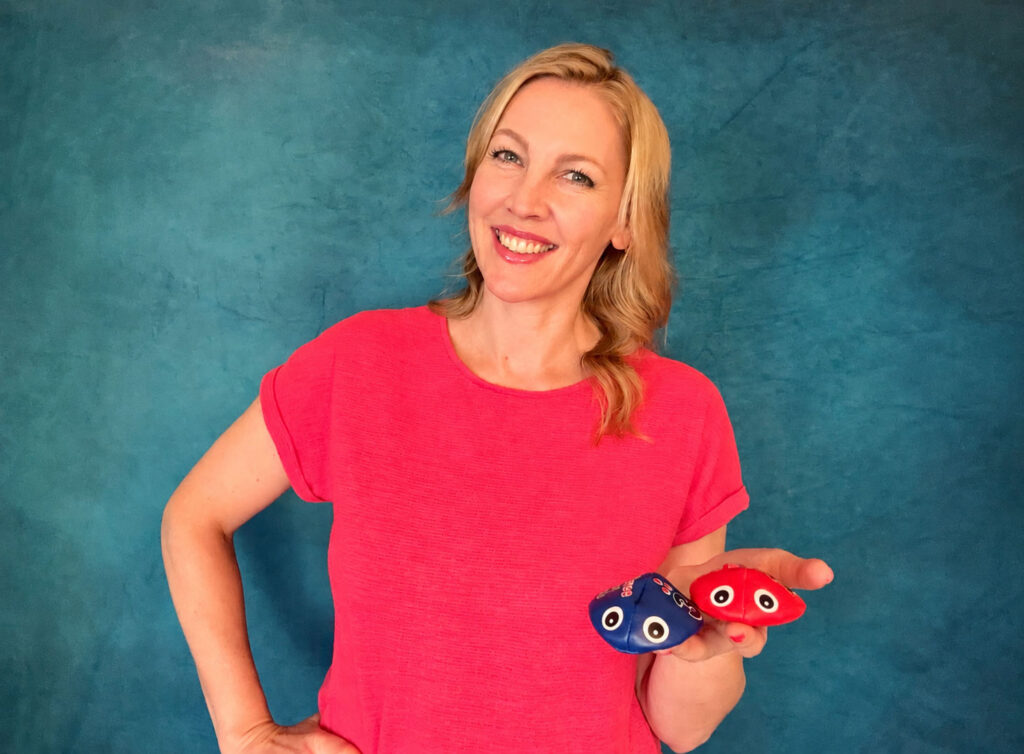 Anja Mentzendorff lächelt und hält zwei bunte Sandsäckchen mit Augen in der Hand
